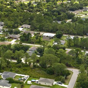 Aerial view of small town America suburban landscape with private homes between green palm trees in Florida quiet residential area.